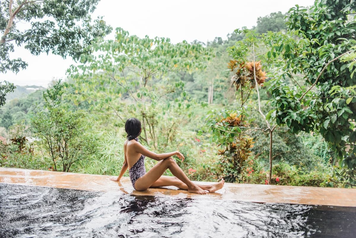 A guest sits at the edge of the saltwater infinity pool overlooking the Busay forest valley