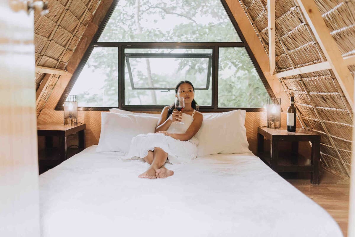 Inside a premium A-frame treehut with a memory-foam king bed and a forest window