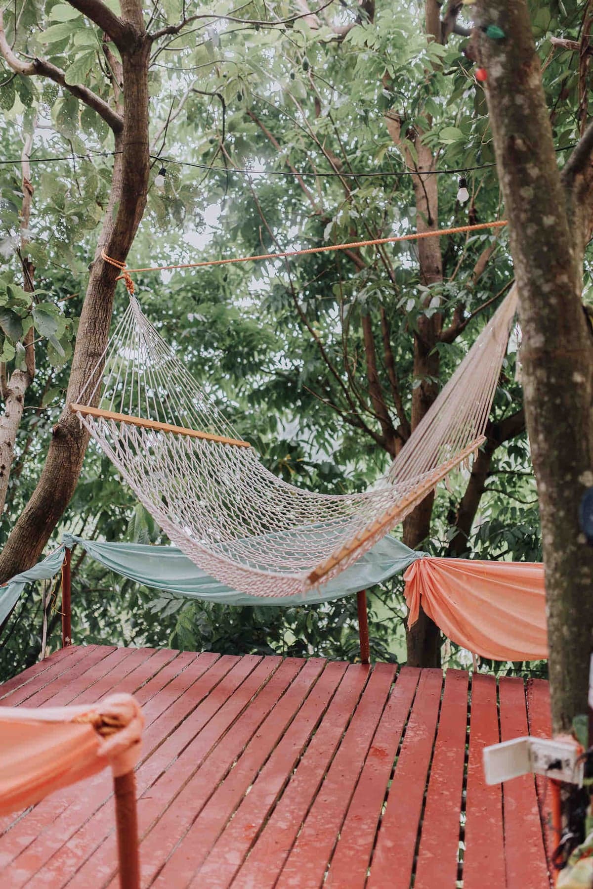 A suspended balcony hammock on a premium treehut deck over the forest